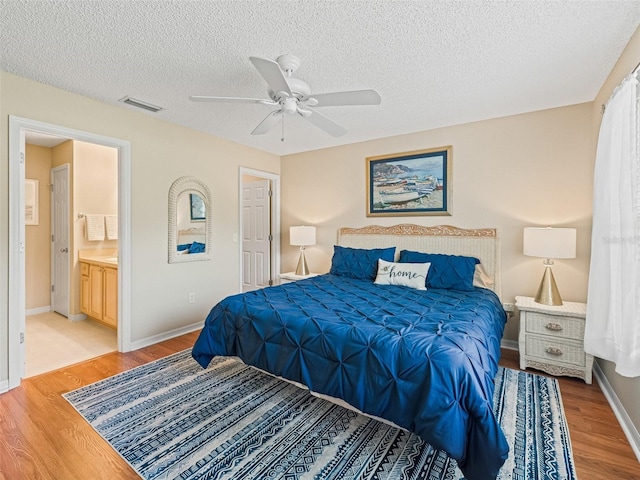 2369 Five Forks Trl, The Villages, FL 32162 - bedroom with light wood-type flooring, a textured ceiling, ceiling fan, and connected bathroom