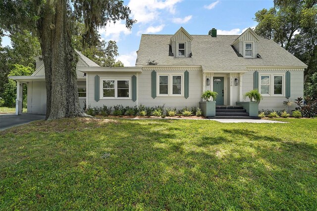 126 E Beach St, Groveland, FL 34736 - cape cod home featuring a front yard, a shingled roof, and a chimney