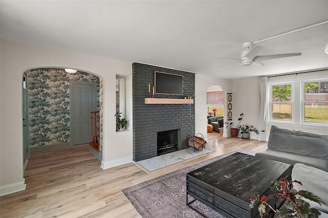 126 E Beach St, Groveland, FL 34736 - living area featuring light wood finished floors, arched walkways, a ceiling fan, and a fireplace