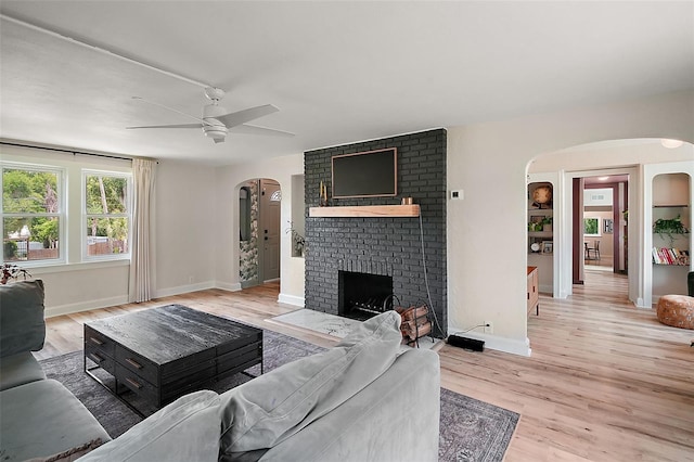 126 E Beach St, Groveland, FL 34736 - living area with arched walkways, a ceiling fan, a brick fireplace, and light wood finished floors