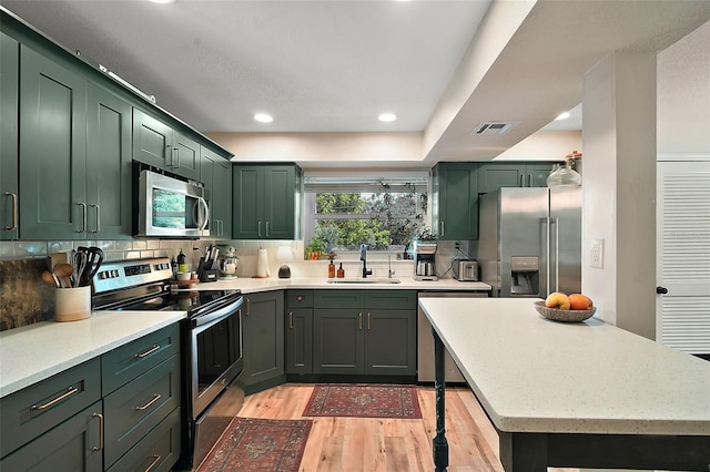 126 E Beach St, Groveland, FL 34736 - kitchen with stainless steel appliances, green cabinets, light wood-type flooring, recessed lighting, and backsplash