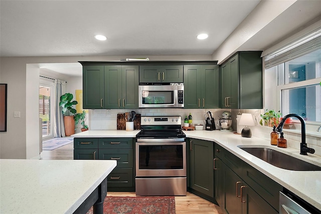 126 E Beach St, Groveland, FL 34736 - kitchen featuring stainless steel appliances, green cabinets, backsplash, light wood-style flooring, and recessed lighting