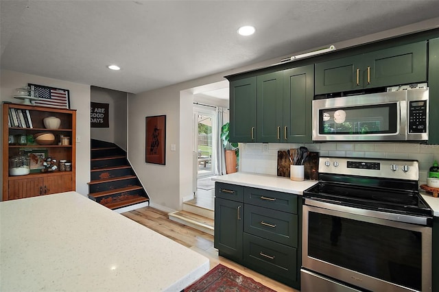 126 E Beach St, Groveland, FL 34736 - kitchen with stainless steel appliances, green cabinetry, light countertops, backsplash, and recessed lighting
