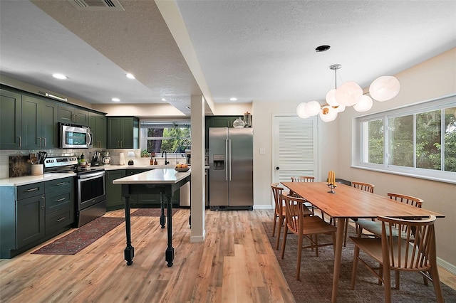 126 E Beach St, Groveland, FL 34736 - kitchen featuring stainless steel appliances, green cabinets, light wood-style floors, light countertops, and a textured ceiling