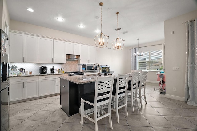 9153 Carmela Ave, Davenport, FL 33897 - kitchen featuring a chandelier, range hood, light tile patterned floors, backsplash, and white cabinets