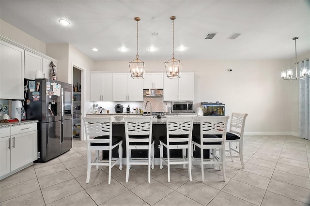 9153 Carmela Ave, Davenport, FL 33897 - kitchen featuring a chandelier, stainless steel appliances, backsplash, light tile patterned floors, and a kitchen bar