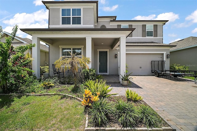 9153 Carmela Ave, Davenport, FL 33897 - view of front of house with a porch, stucco siding, decorative driveway, and an attached garage