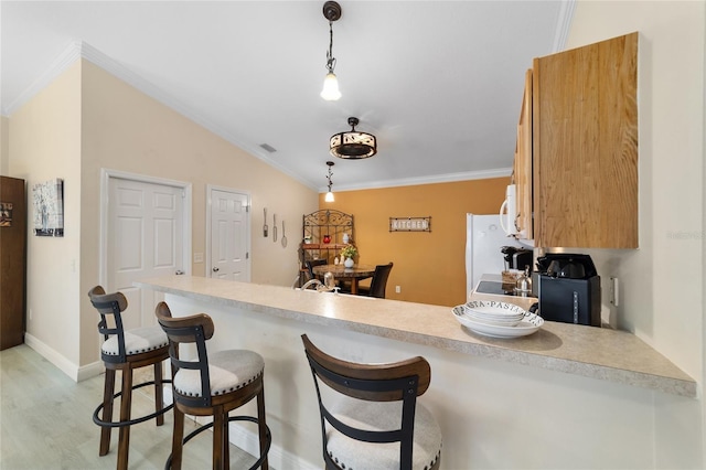 2237 Jetta Way, The Villages, FL 32162 - kitchen with ornamental molding, a peninsula, light countertops, hanging light fixtures, and light wood-type flooring