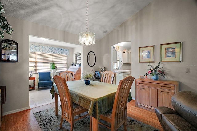 1007 Diego Ct, The Villages, FL 32159 - dining room with arched walkways, a chandelier, light wood-style floors, and lofted ceiling