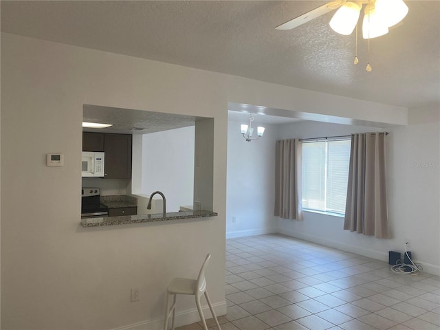 624 Australian Way, Davenport, FL 33897 - kitchen with stainless steel range with electric stovetop, white microwave, a textured ceiling, light tile patterned floors, and ceiling fan