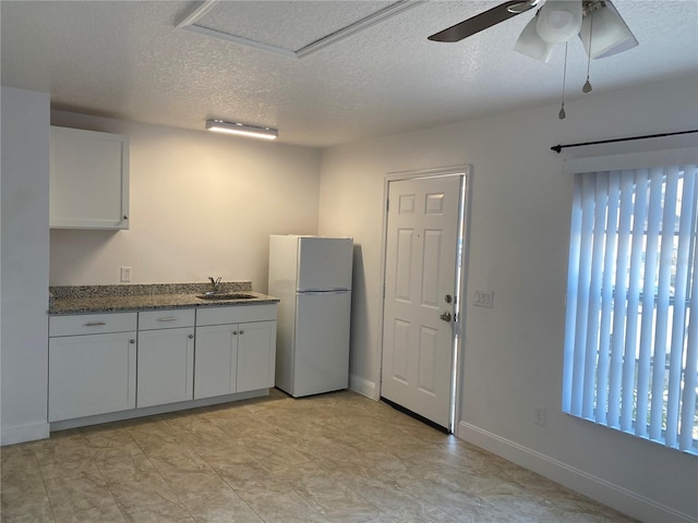 624 Australian Way, Davenport, FL 33897 - kitchen with freestanding refrigerator, a textured ceiling, white cabinets, and ceiling fan