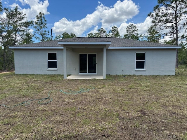 6769 N Waterman Dr, Dunnellon, FL 34433 - rear view of house featuring stucco siding, a lawn, a shingled roof, and a patio area