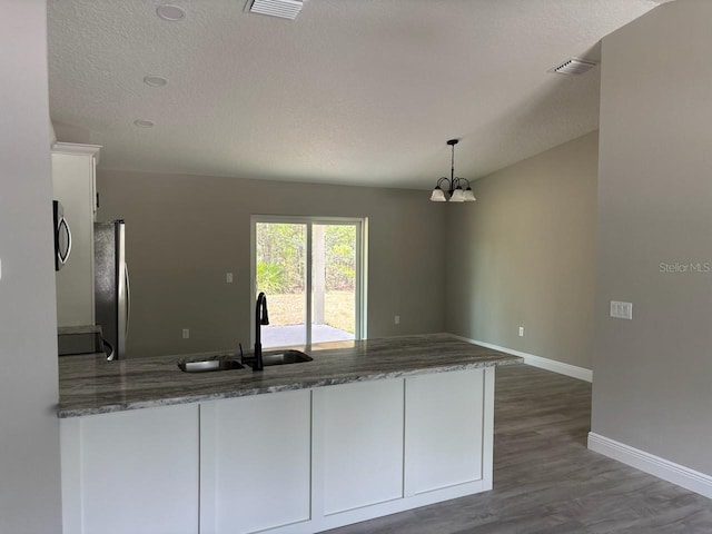 6769 N Waterman Dr, Dunnellon, FL 34433 - kitchen with white cabinetry, a peninsula, stainless steel appliances, a chandelier, and dark wood-style floors
