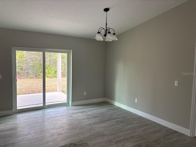 6769 N Waterman Dr, Dunnellon, FL 34433 - unfurnished room with a chandelier, wood finished floors, and a textured ceiling