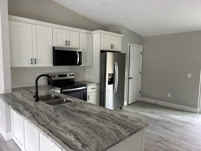 6769 N Waterman Dr, Dunnellon, FL 34433 - kitchen featuring appliances with stainless steel finishes, lofted ceiling, light stone counters, backsplash, and white cabinets
