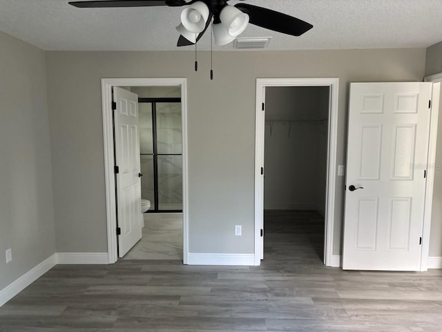 6769 N Waterman Dr, Dunnellon, FL 34433 - unfurnished bedroom with a spacious closet, a closet, wood finished floors, ensuite bathroom, and a textured ceiling