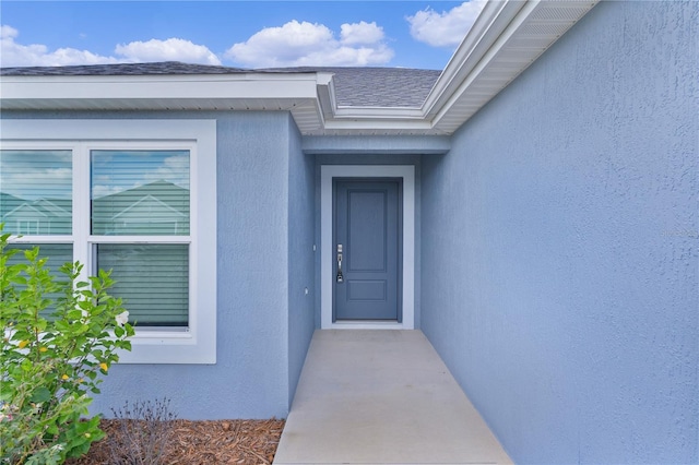 6949 Minchew Cir, The Villages, FL 34762 - view of exterior entry with stucco siding and roof with shingles