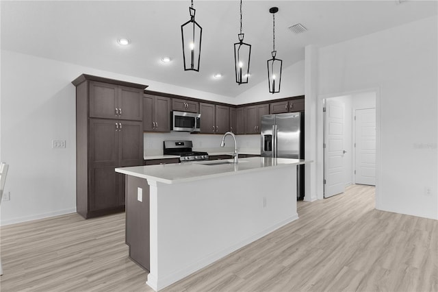 6949 Minchew Cir, The Villages, FL 34762 - kitchen featuring stainless steel appliances, dark brown cabinets, light countertops, light wood-type flooring, and an island with sink