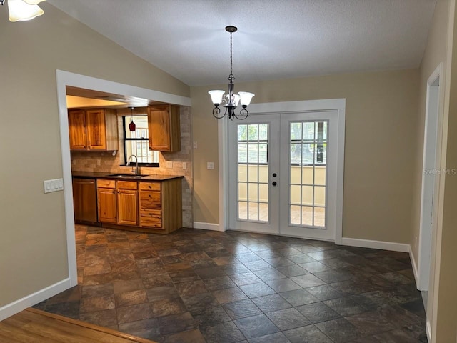 7186 N Whippoorwill Ter, Hernando, FL 34442 - kitchen featuring brown cabinets, stainless steel dishwasher, dark stone finish floors, french doors, and a chandelier