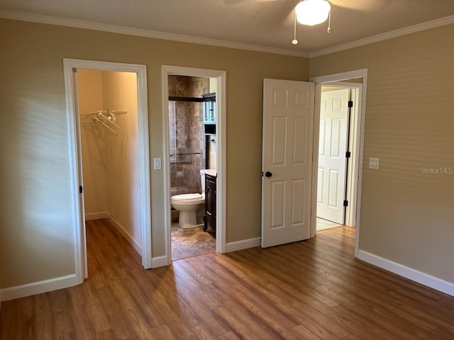 7186 N Whippoorwill Ter, Hernando, FL 34442 - unfurnished bedroom featuring a walk in closet, wood finished floors, a closet, ornamental molding, and ensuite bath