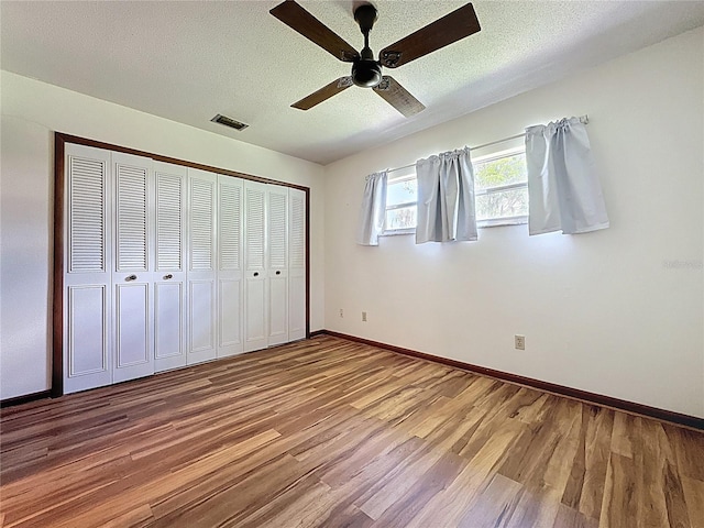11401 Cypress Dr, Clermont, FL 34711 - unfurnished bedroom featuring wood finished floors, a textured ceiling, a closet, and a ceiling fan