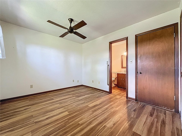 11401 Cypress Dr, Clermont, FL 34711 - unfurnished bedroom featuring wood finished floors, connected bathroom, and a ceiling fan