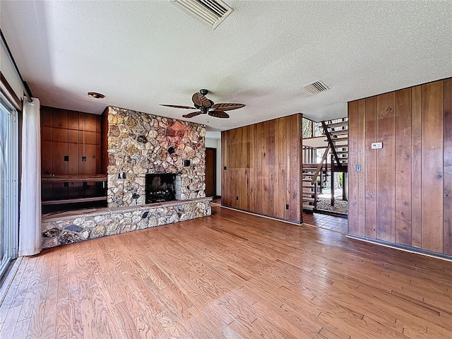 11401 Cypress Dr, Clermont, FL 34711 - unfurnished living room featuring wood walls, ceiling fan, wood finished floors, stairway, and a textured ceiling
