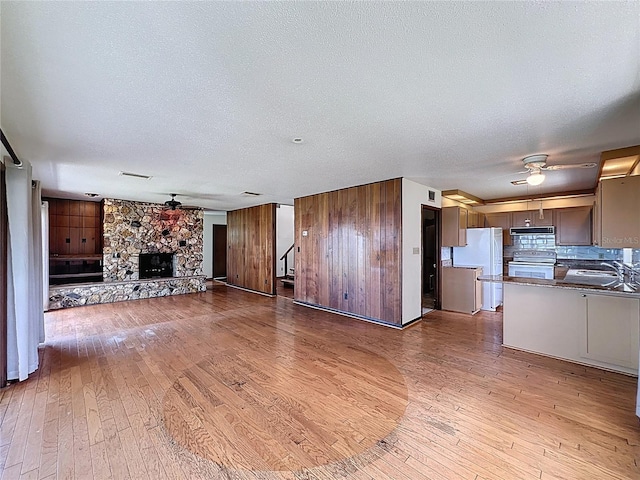 11401 Cypress Dr, Clermont, FL 34711 - unfurnished living room with ceiling fan, hardwood / wood-style flooring, a fireplace, a textured ceiling, and wood walls