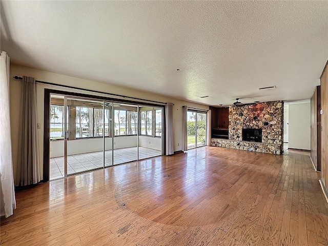 11401 Cypress Dr, Clermont, FL 34711 - unfurnished living room with a textured ceiling, light wood-style floors, a fireplace, and ceiling fan