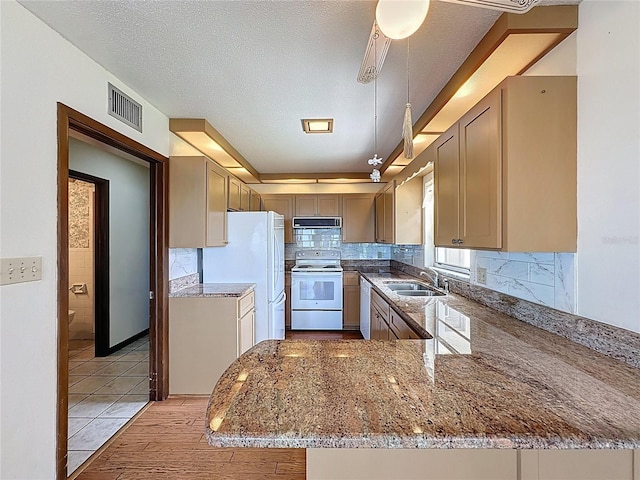 11401 Cypress Dr, Clermont, FL 34711 - kitchen with white appliances, light stone counters, exhaust hood, backsplash, and a peninsula