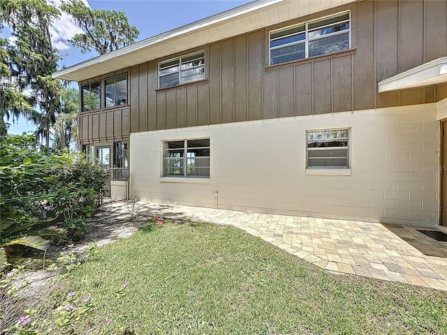 11401 Cypress Dr, Clermont, FL 34711 - view of side of home featuring board and batten siding, a patio, and a lawn