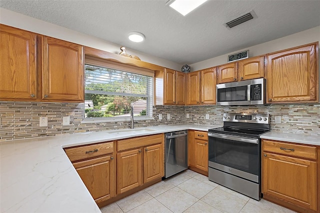 1002 Amarillo Pl, The Villages, FL 32159 - kitchen featuring appliances with stainless steel finishes, a textured ceiling, light tile patterned flooring, backsplash, and brown cabinetry