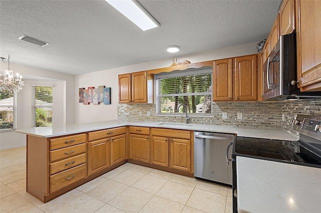 1002 Amarillo Pl, The Villages, FL 32159 - kitchen featuring stainless steel appliances, a peninsula, a textured ceiling, backsplash, and light countertops