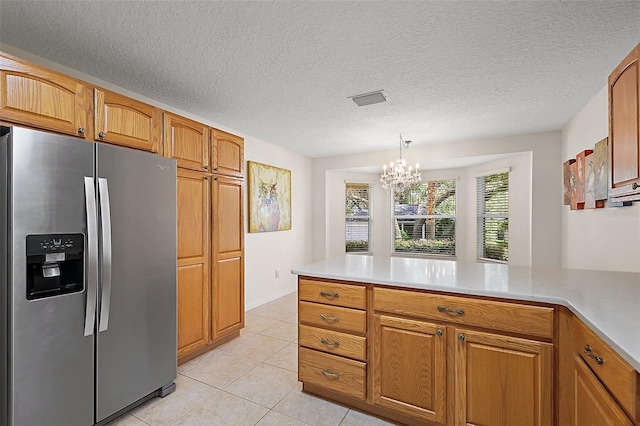 1002 Amarillo Pl, The Villages, FL 32159 - kitchen with stainless steel fridge, light countertops, a chandelier, a peninsula, and a textured ceiling