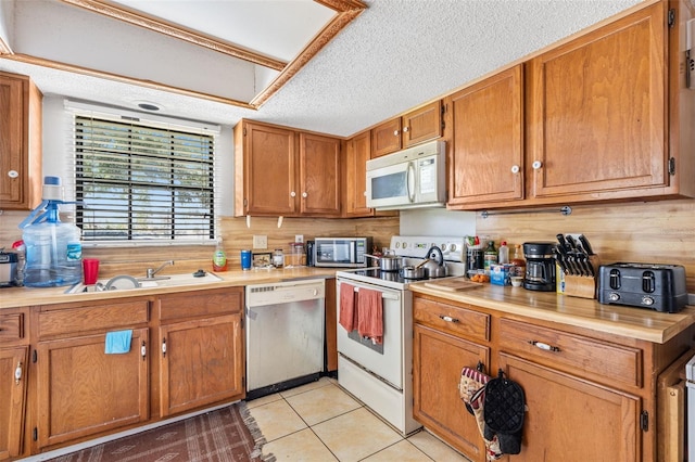 3401 Sunrise Villas Ct S, Tampa, FL 33614 - kitchen with stainless steel appliances, light countertops, light tile patterned flooring, brown cabinetry, and a textured ceiling