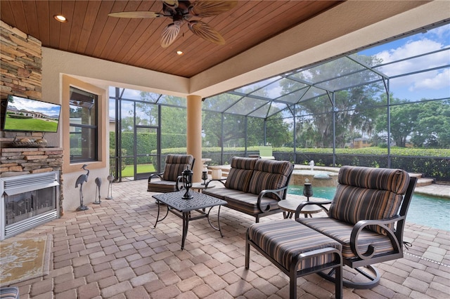view of patio featuring a hot tub, an outdoor stone fireplace, an outdoor pool, and glass enclosure
