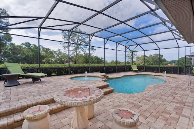 view of swimming pool featuring a patio area, a lanai, a pool with connected hot tub, and view of wooded area