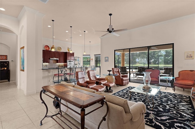 living area featuring light tile patterned floors, a ceiling fan, ornamental molding, arched walkways, and recessed lighting