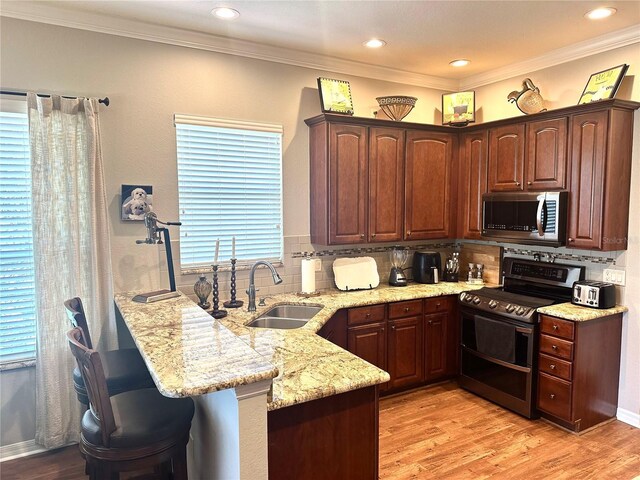 12183 SE 178th St, Summerfield, FL 34491 - kitchen featuring stainless steel appliances, a peninsula, tasteful backsplash, light stone countertops, and light wood finished floors