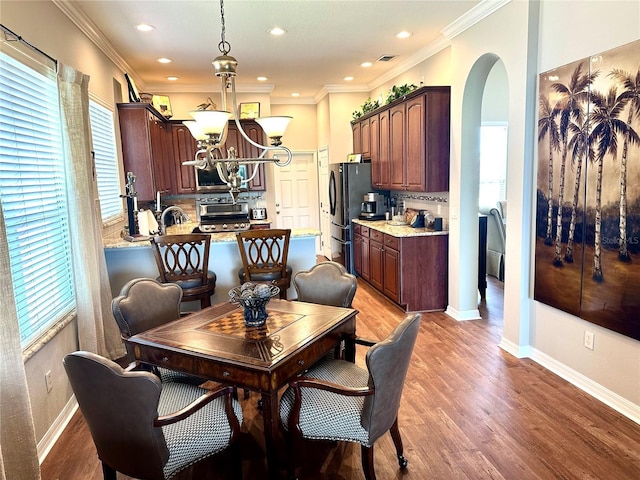 12183 SE 178th St, Summerfield, FL 34491 - dining area featuring arched walkways, healthy amount of natural light, light wood-style floors, recessed lighting, and crown molding
