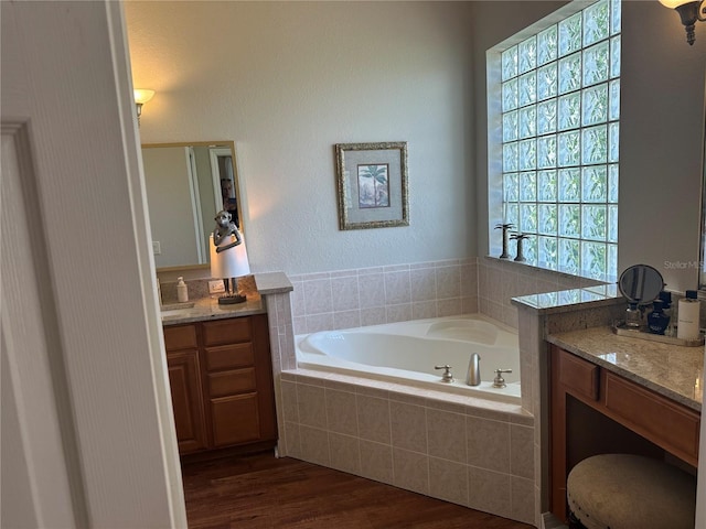 12183 SE 178th St, Summerfield, FL 34491 - bathroom featuring two vanities, a garden tub, wood finished floors, and healthy amount of natural light