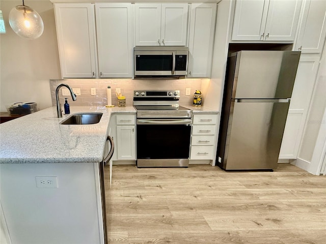 3607 Umbrella Tree Ln, Oxford, FL 34484 - kitchen with appliances with stainless steel finishes, light wood finished floors, a peninsula, and decorative backsplash