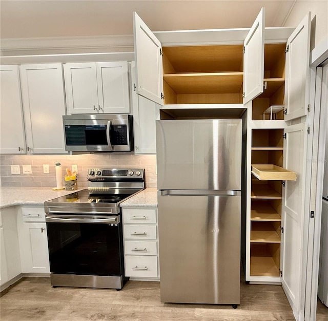3607 Umbrella Tree Ln, Oxford, FL 34484 - kitchen featuring appliances with stainless steel finishes, open shelves, light wood-style flooring, white cabinetry, and crown molding