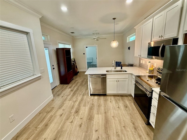 3607 Umbrella Tree Ln, Oxford, FL 34484 - kitchen featuring appliances with stainless steel finishes, a peninsula, white cabinets, light countertops, and crown molding