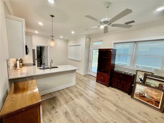 3607 Umbrella Tree Ln, Oxford, FL 34484 - kitchen featuring crown molding, a peninsula, a ceiling fan, white cabinetry, and light stone counters