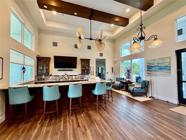 3607 Umbrella Tree Ln, Oxford, FL 34484 - kitchen featuring dark wood-type flooring, a high ceiling, glass insert cabinets, hanging light fixtures, and light stone counters