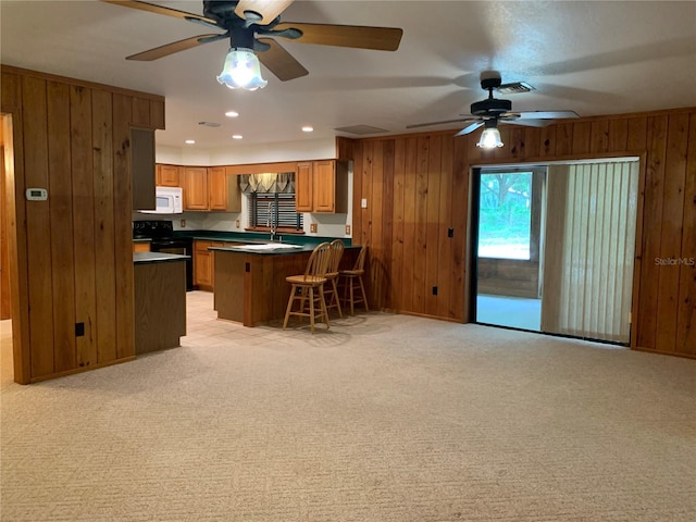 2530 Shady Ln, Groveland, FL 34736 - kitchen with wood walls, dark countertops, brown cabinets, ceiling fan, and white microwave
