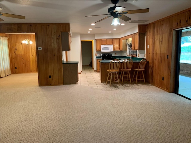2530 Shady Ln, Groveland, FL 34736 - kitchen featuring ceiling fan, white microwave, wooden walls, light colored carpet, and dark countertops