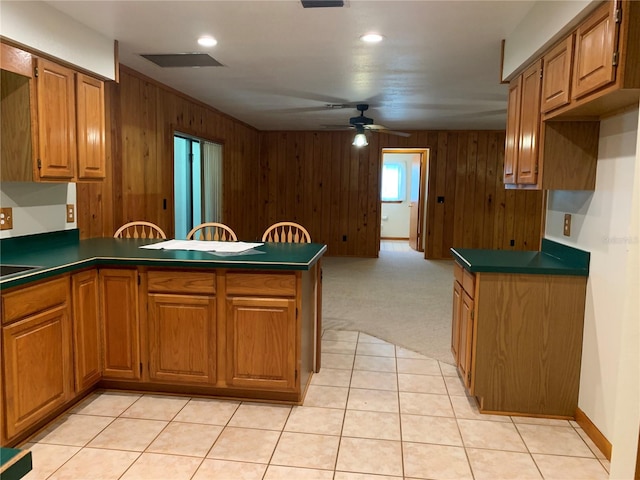 2530 Shady Ln, Groveland, FL 34736 - kitchen with a peninsula, wood walls, brown cabinets, a ceiling fan, and dark countertops