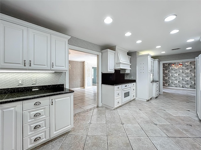 504 Banning Beach Rd, Tavares, FL 32778 - kitchen with custom exhaust hood, white oven, white cabinetry, tasteful backsplash, and light tile patterned flooring